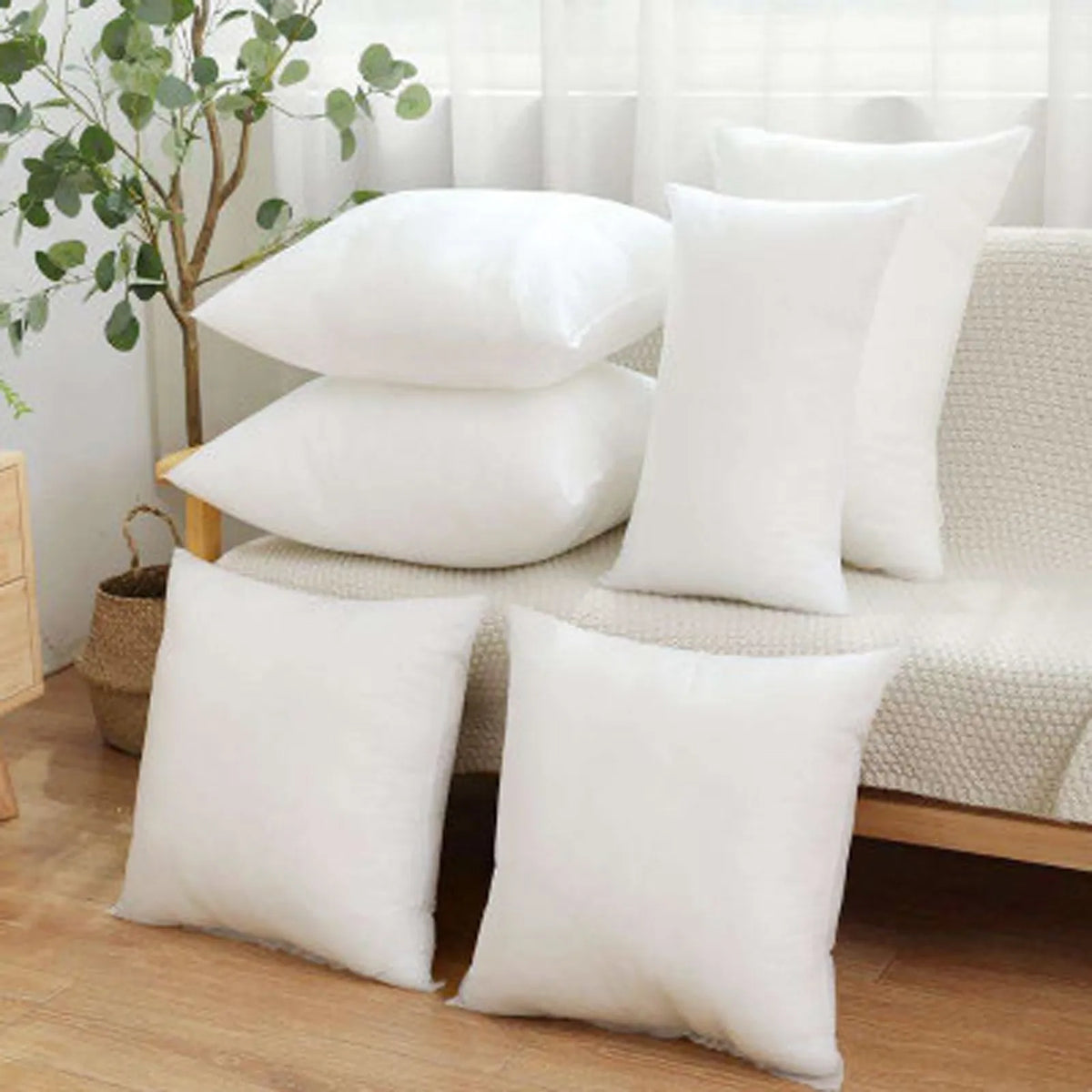 A collection of white soft cotton-padded headboard cushions arranged on a light-colored sofa.