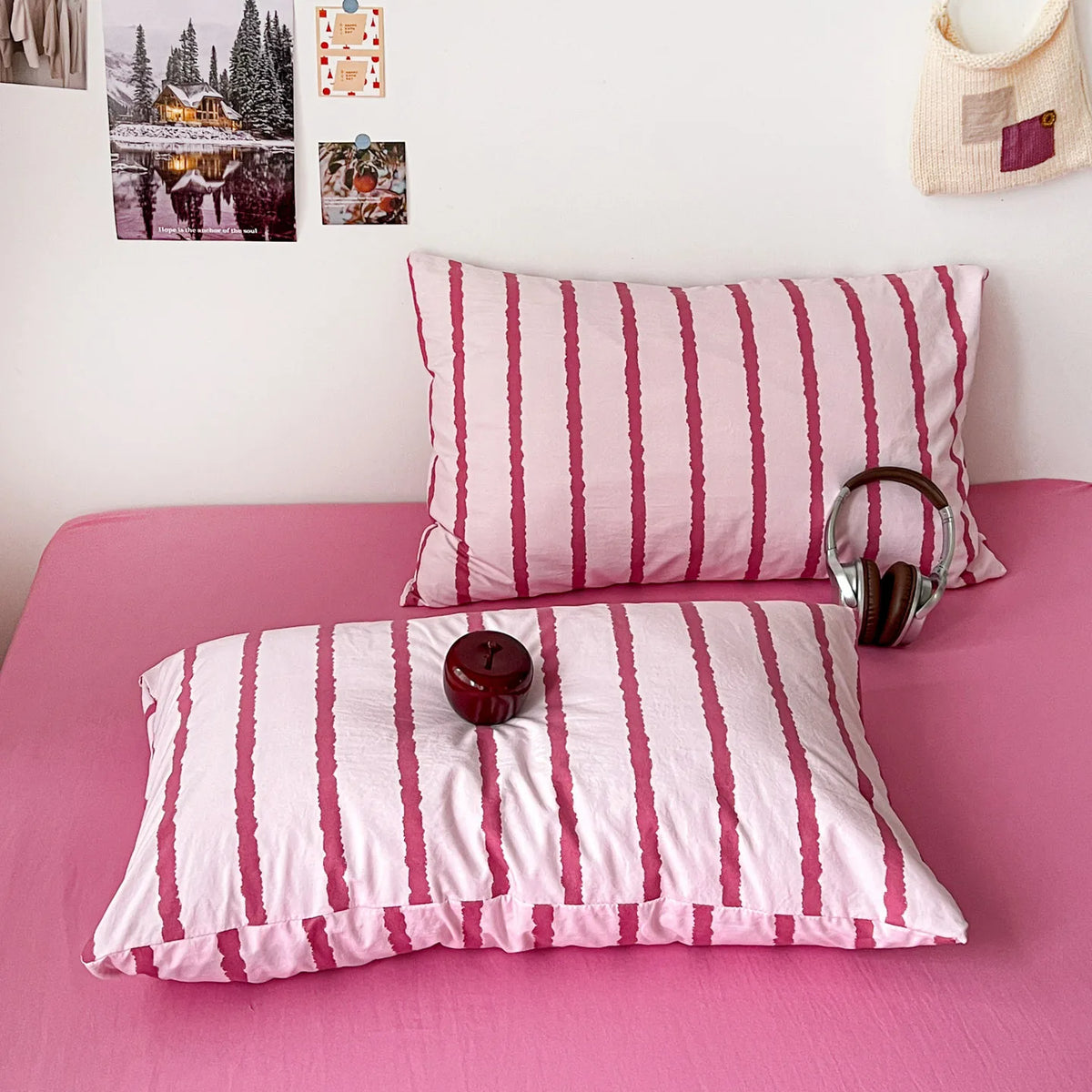 Pink striped duvet cover set with matching pillowcases and a wooden clock on a pink bed.