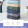 A stack of six textured cotton face towels in various shades of green and blue on a white surface.