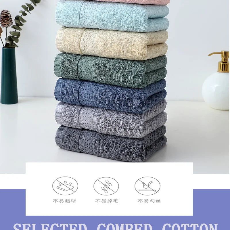 A stack of six textured cotton face towels in various shades of green and blue on a white surface.