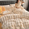 A woman is relaxing on a bed covered in fluffy cream-colored plush rabbit hair bedding.