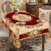 A red and cream floral tablecloth with vintage rose print displayed on a wooden table.