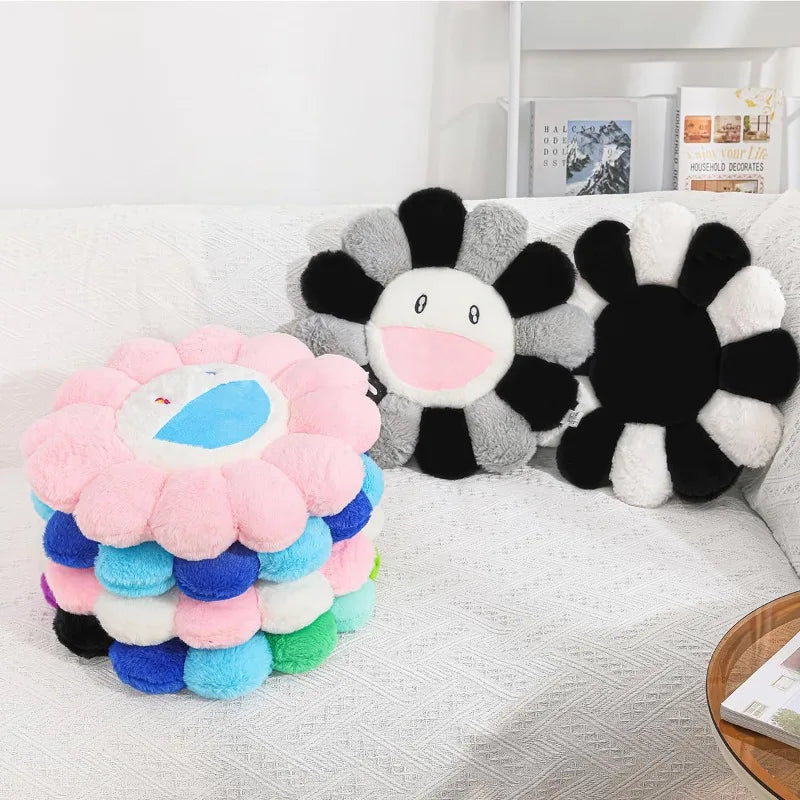 A collection of cozy sunflower plush cushions in pink, gray, and black with smile faces.