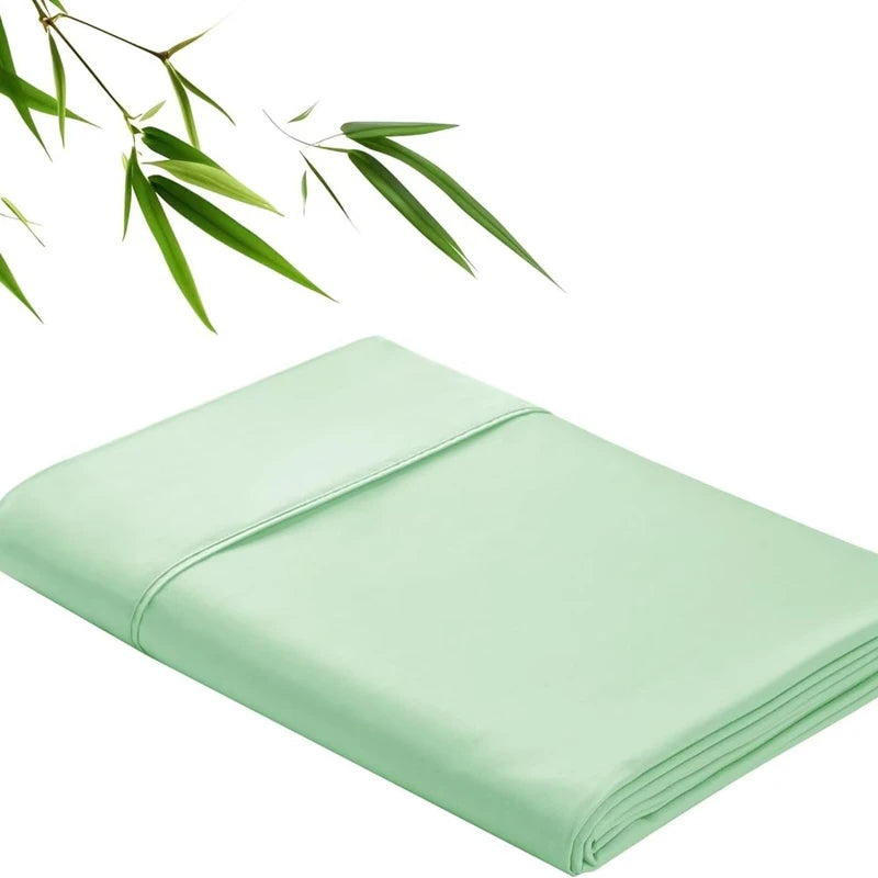 Light green bamboo fiber flat bed sheet folded neatly with green leaves in the background