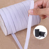 A hand is holding and unwrapping a white elastic band for garments, showing the coiled material.
