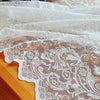 White vintage lace tablecloth draped over a wooden surface.