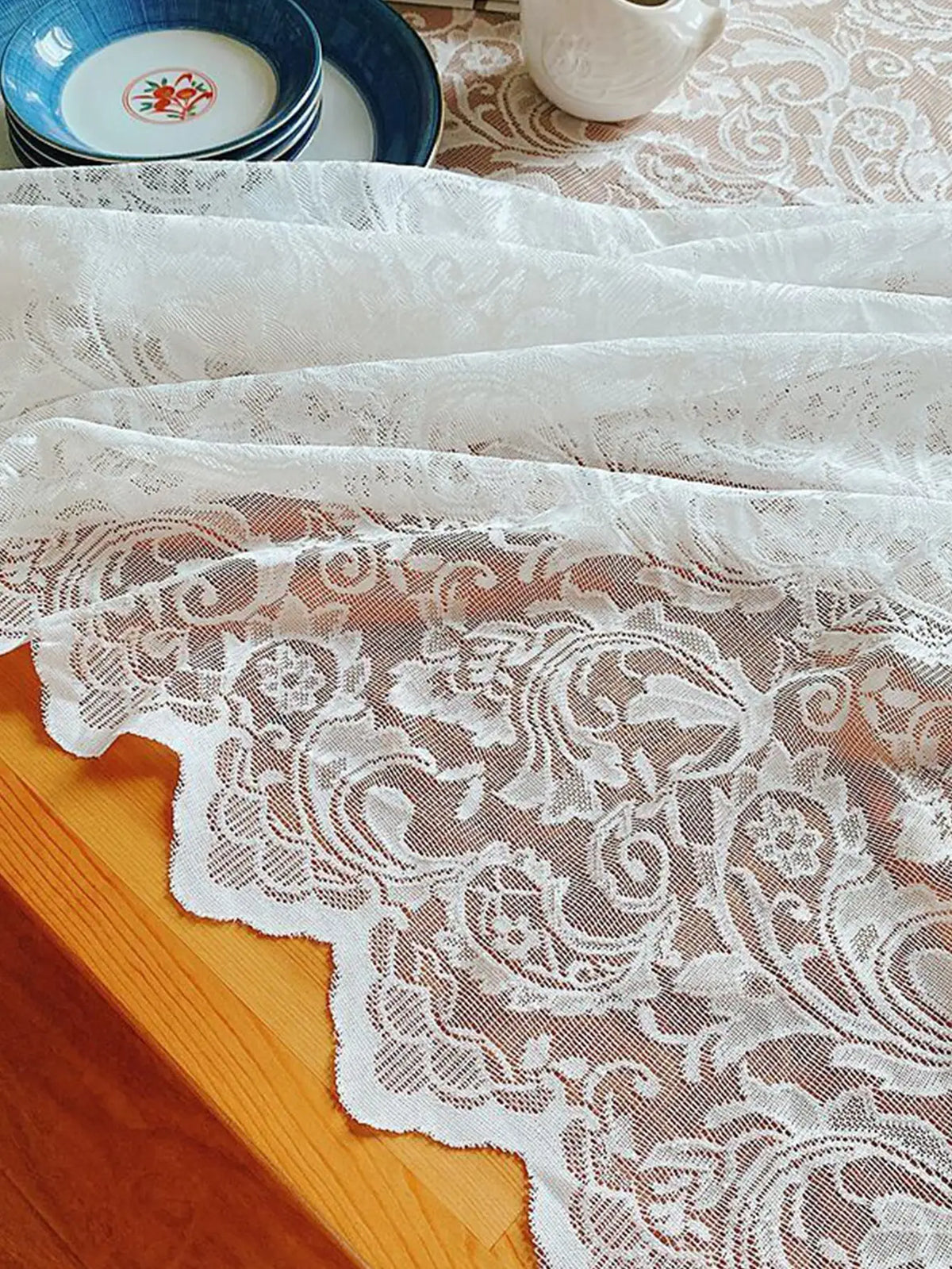 White vintage lace tablecloth draped over a wooden surface.