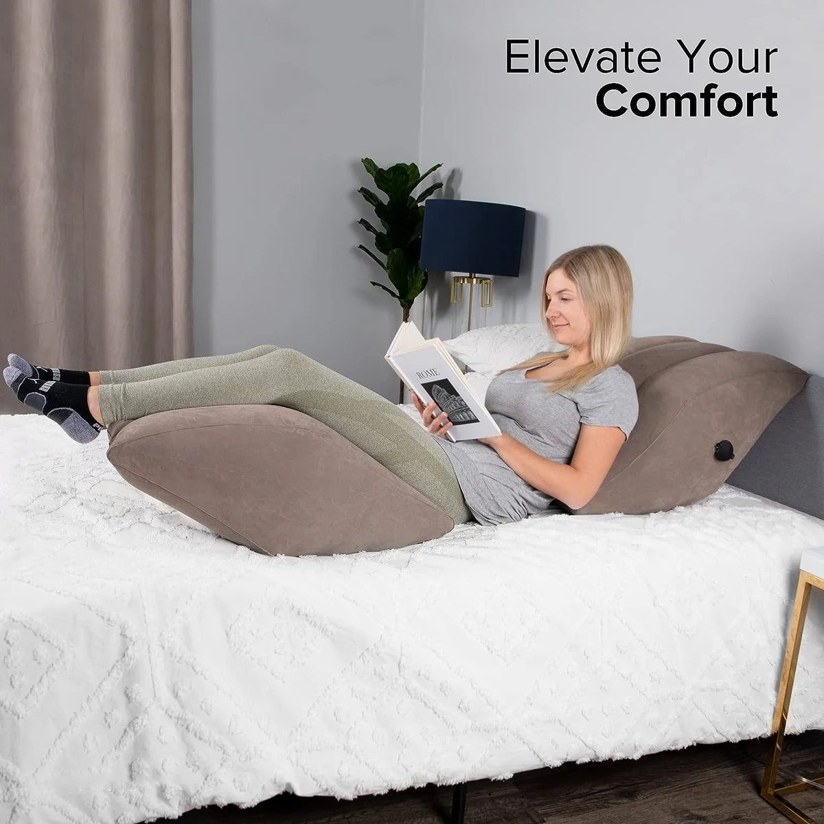 A woman is relaxing on a bed using an inflatable leg elevation pillow for comfort.