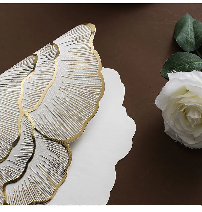 Gold plated peony coasters with textured leaves placed on a brown surface next to a white rose.