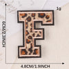 A black iron-on patch shaped like the letter F with a leopard print design.
