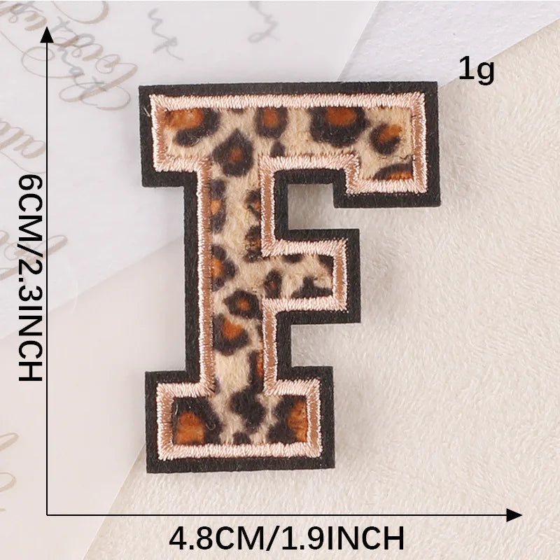 A black iron-on patch shaped like the letter F with a leopard print design.