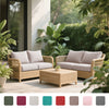 A beige outdoor wicker sofa set with light cushions and a matching coffee table set in a lush garden setting.