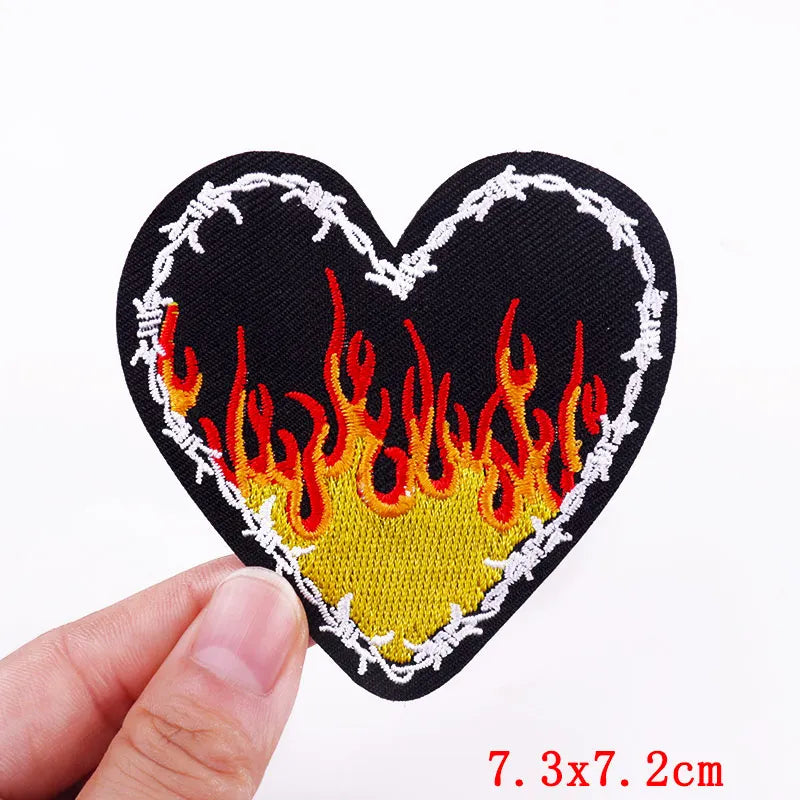 Black heart shaped embroidery patch featuring a yellow flame design outlined in white thread