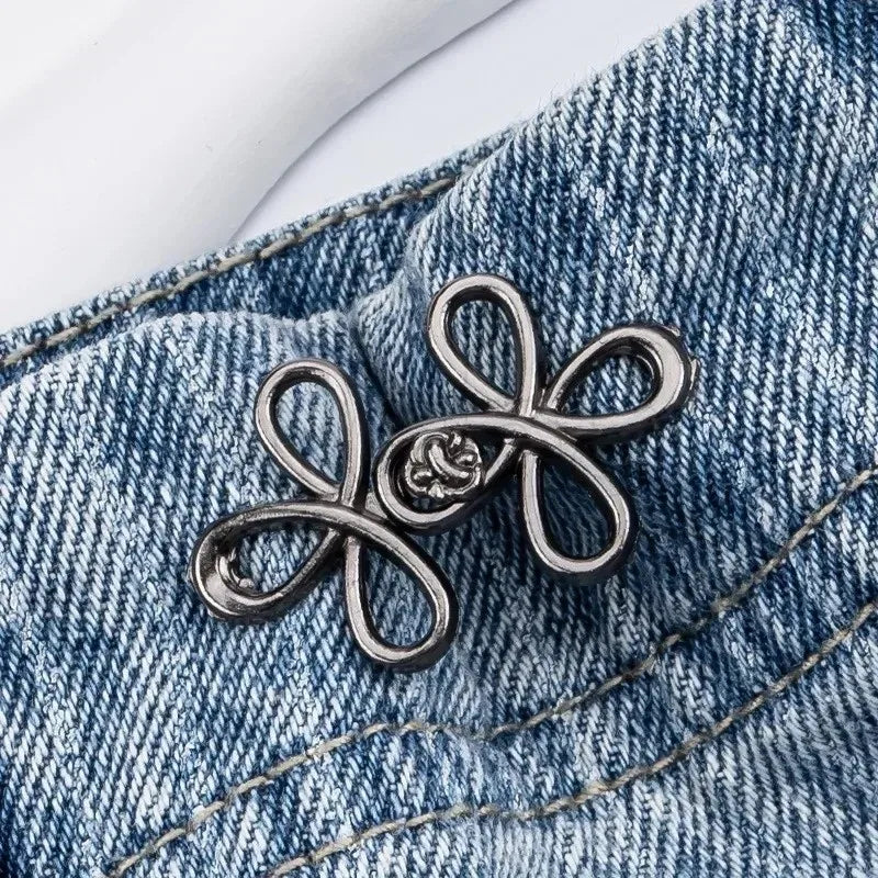 Silver adjustable leaf clover waist tightener clipped onto blue denim fabric.