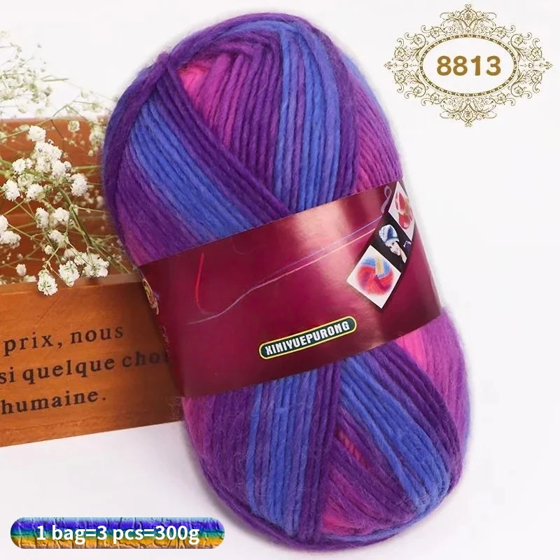 A skein of gradient dyed purple and blue wool yarn with a brown label and a gold stamp.