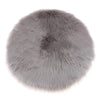A round, plush gray faux fur sheepskin area rug with a soft, fluffy texture.
