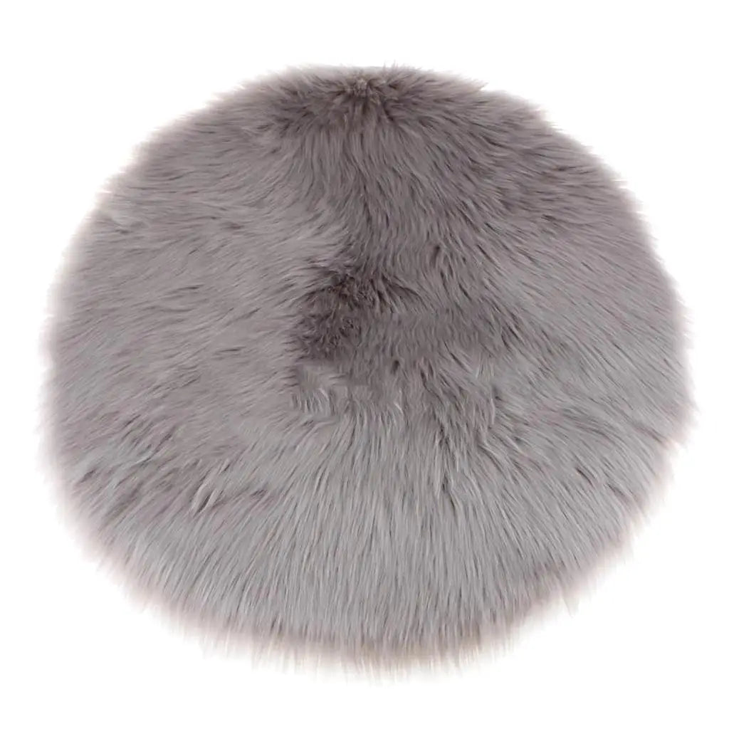 A round, plush gray faux fur sheepskin area rug with a soft, fluffy texture.