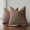 A brown linen textured throw pillow cover resting on a wooden surface.
