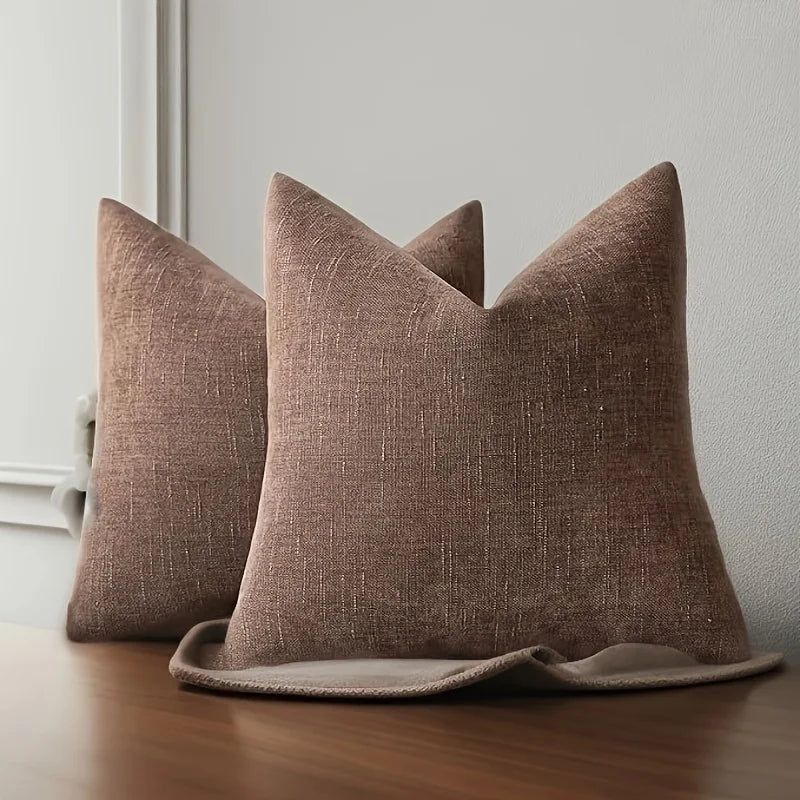 A brown linen textured throw pillow cover resting on a wooden surface.