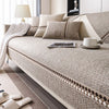 A beige linen sofa cover with neutral pillows and a white throw blanket on a modern sofa.