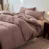 A close-up of a mauve cotton yarn-dyed duvet cover with matching pillows on a bed.