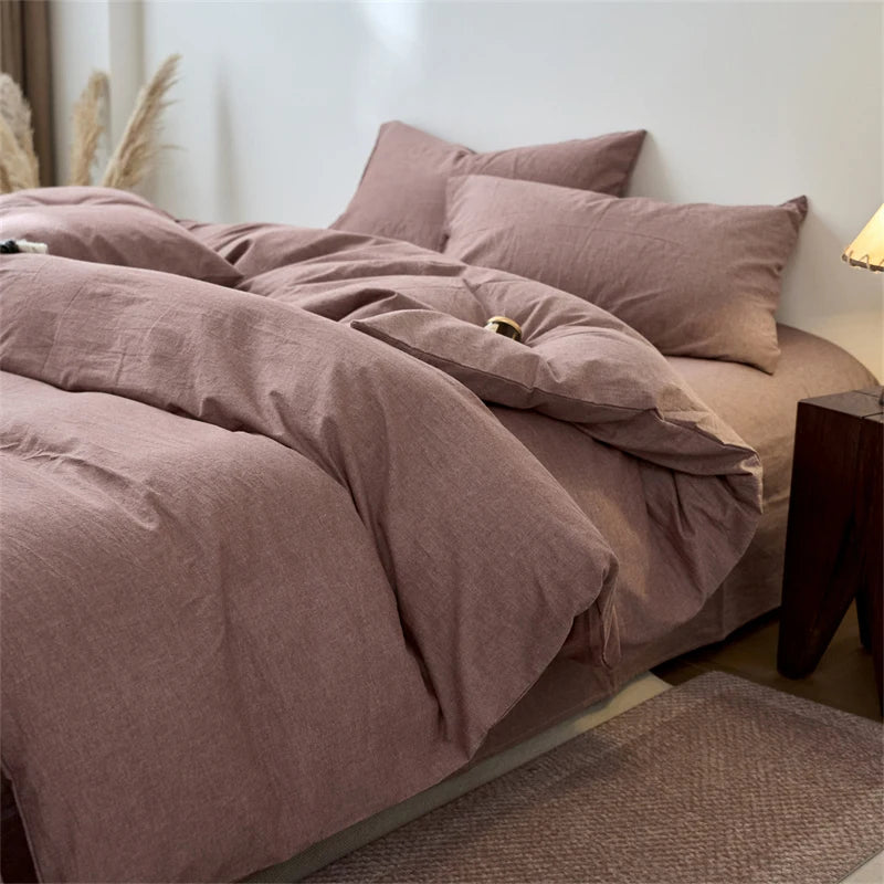 A close-up of a mauve cotton yarn-dyed duvet cover with matching pillows on a bed.