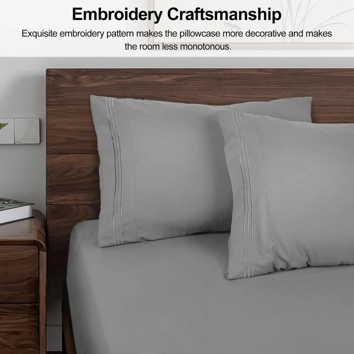 Two gray pillow covers with embroidered detailing displayed on a bed.