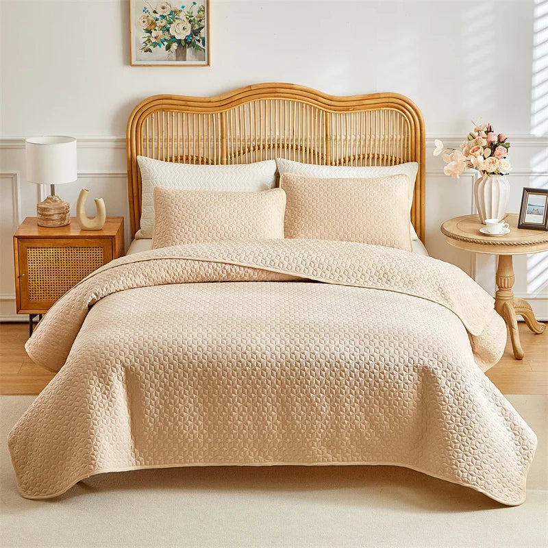A beige plaid quilt set is displayed on a queen bed with a light wood headboard and white linens.