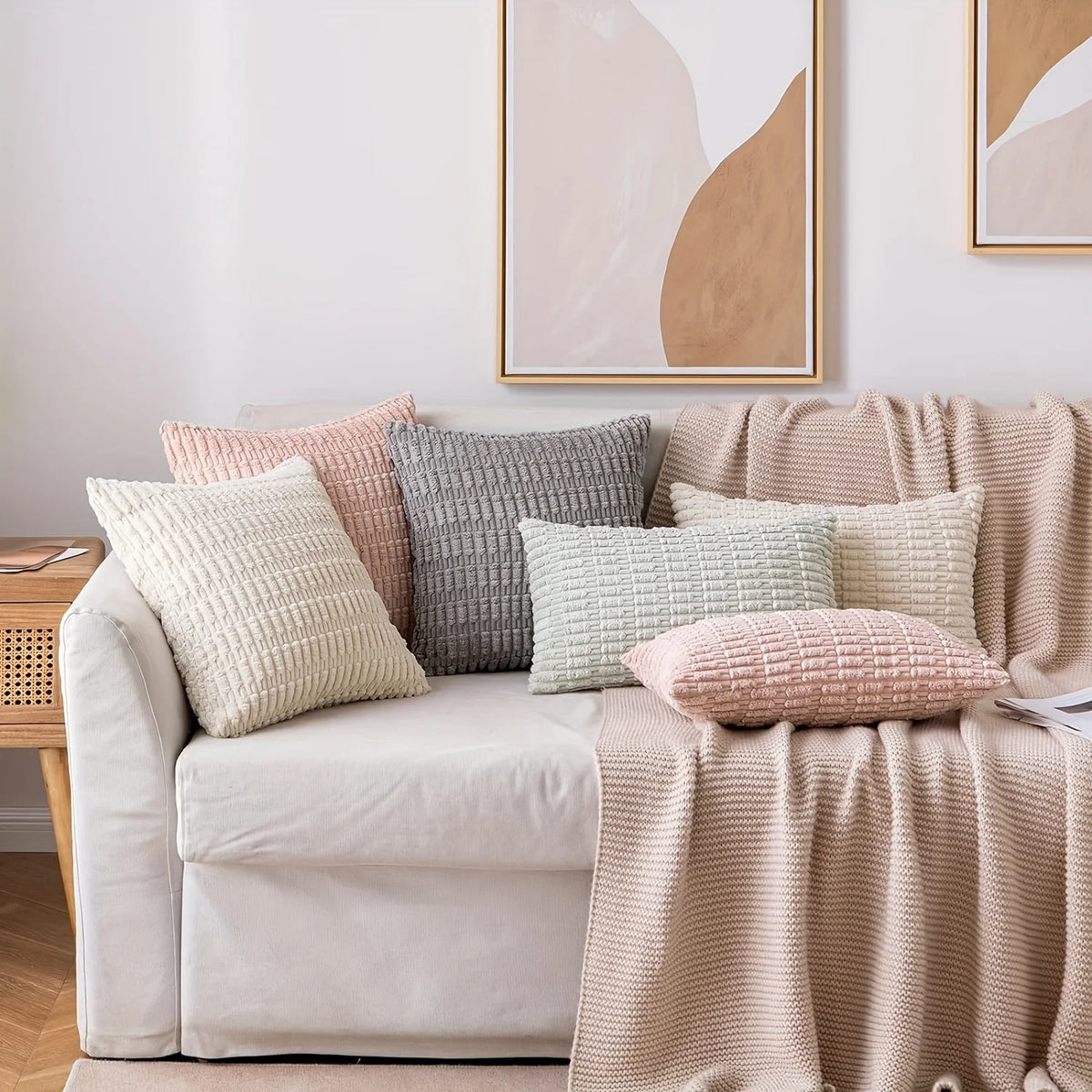 A collection of cream, beige, and dusty rose decorative throw pillows arranged on a light-colored sofa.