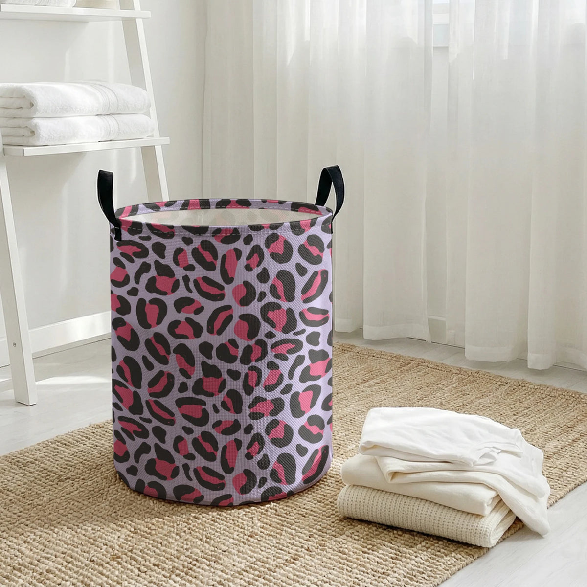A purple and pink leopard print foldable laundry basket sitting on a woven rug next to a white shelf.