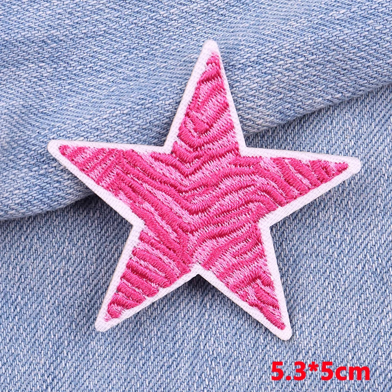 Pink embroidered star patch on blue denim fabric
