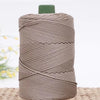 A spool of beige crochet ice rope with a green cap resting on a woven mat.