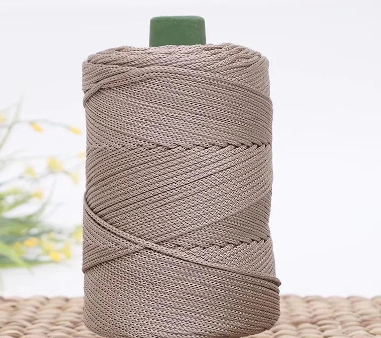A spool of beige crochet ice rope with a green cap resting on a woven mat.