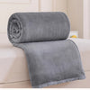 A rolled and unfolded gray flannel throw blanket resting on a white bed.