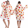 A woman models an oversized patchwork fleece hoodie with a strawberry print in a light cream color.