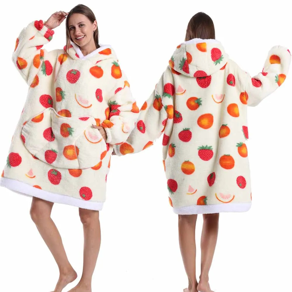 A woman models an oversized patchwork fleece hoodie with a strawberry print in a light cream color.