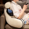 A person is relaxing on a light-colored sofa, leaning against a large, round plush cushion with black and blue accents.