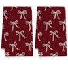 A pair of deep red kitchen towels with white bow patterns.