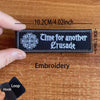 Black embroidered patch with the text Time for another Crusade and a cross emblem on a wooden surface.