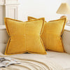 A set of mustard yellow striped corduroy lumbar support pillows resting on a light-colored sofa.