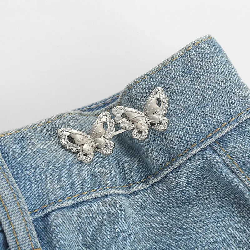 Silver floral butterfly button clips attached to a blue denim fabric