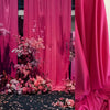 Pink draping stretch fabric used as a backdrop with floral arrangements.