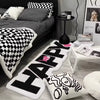 A collection of black and white patterned floor mats, including a large HAPPY mat and decorative cushion.