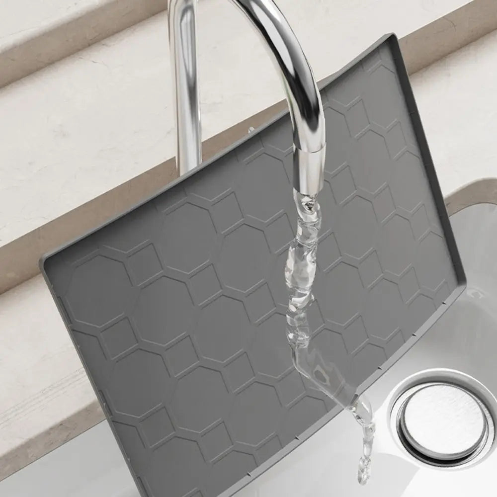 A silver faucet is visible over a gray silicone mat used as an under sink cabinet liner.
