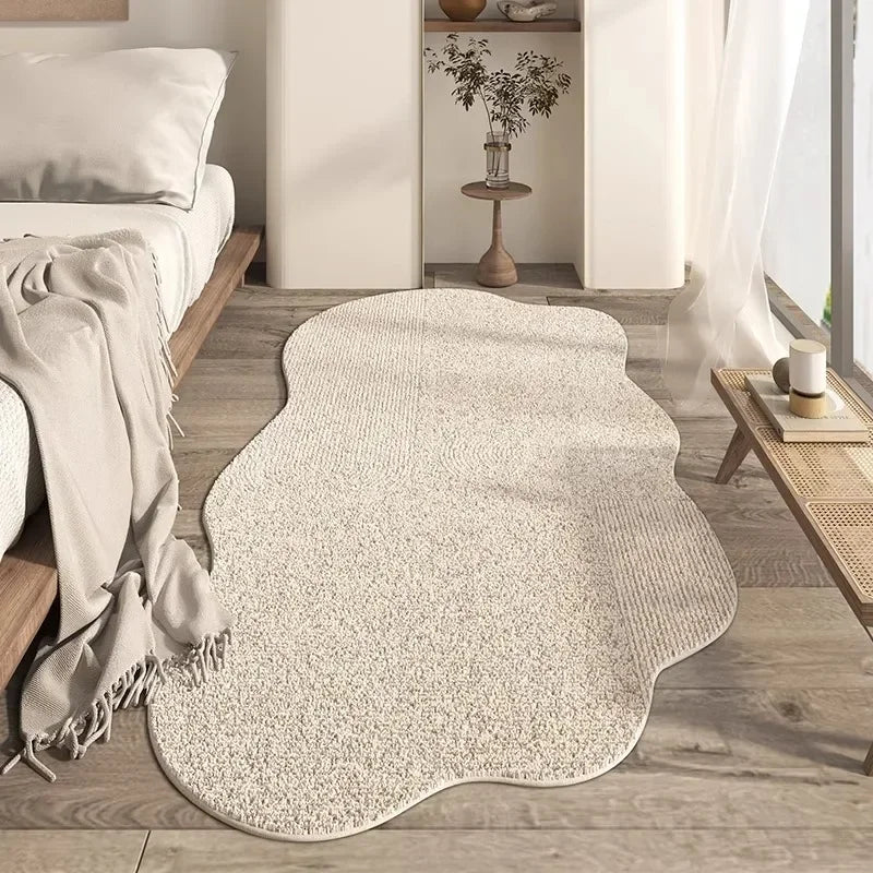 A beige irregular plush area rug placed on a light wood floor in a modern living room setting.