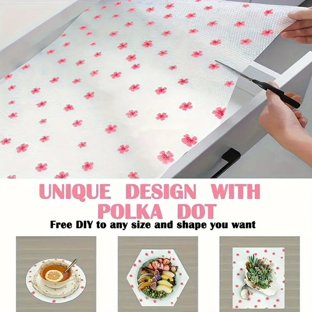 White reusable fridge and cabinet liner pads with a pink polka dot design being cut by a knife