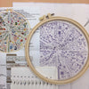 An open embroidery kit showing various floral designs and stitching instructions on paper.