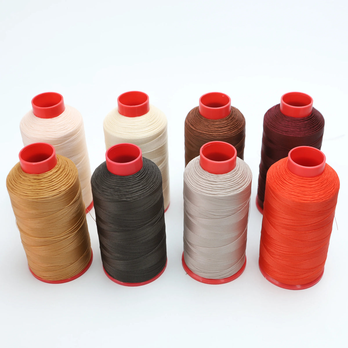 Four spools of heavy duty nylon sewing thread in shades of beige, black, gray, and orange.