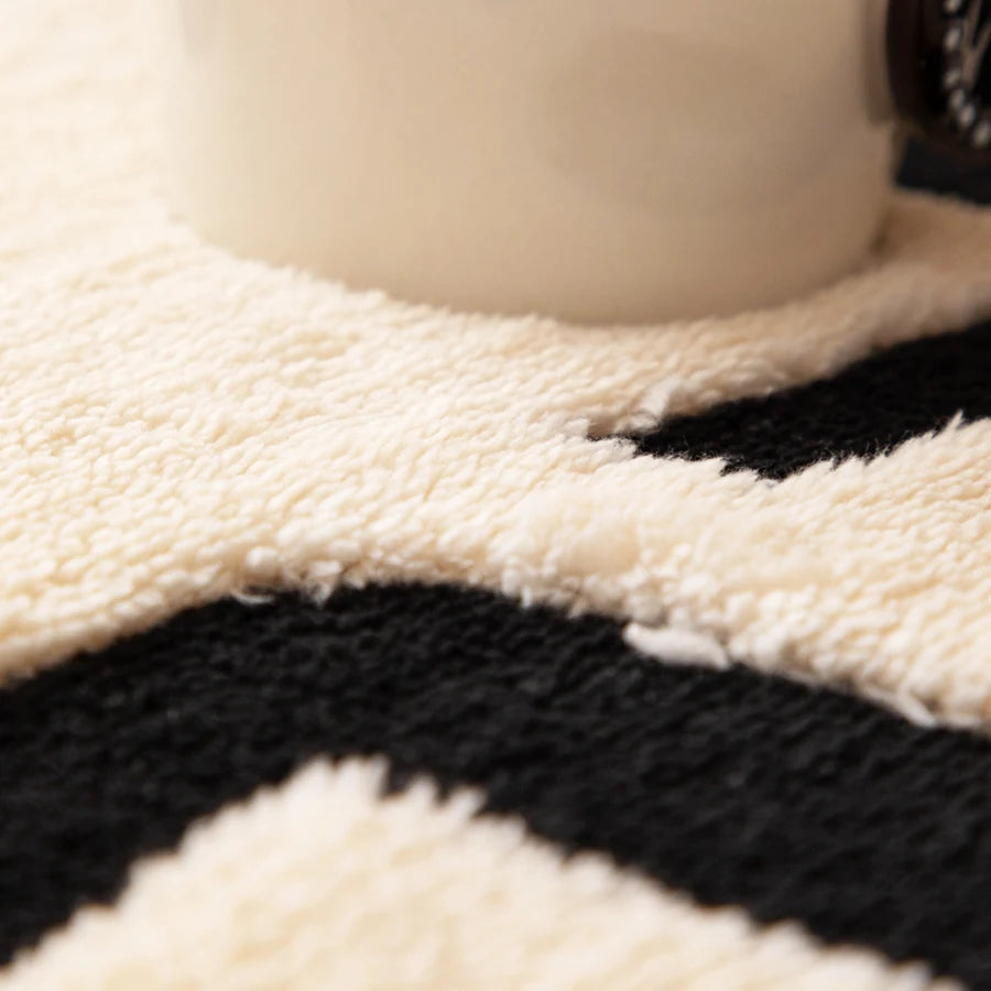 Close-up of a vintage bohemian knit sofa protector featuring black and cream geometric patterns.