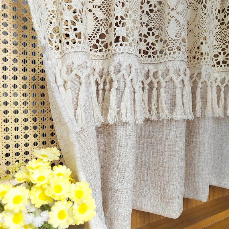 Cream geometric lace short curtains with tasseled trim hanging in a window.